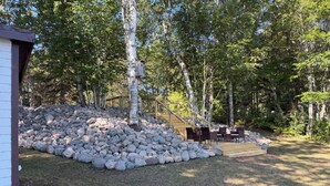 Un jardin avec une terrasse en bois, un mur en pierre et un escalier menant à une autre terrasse en bois.