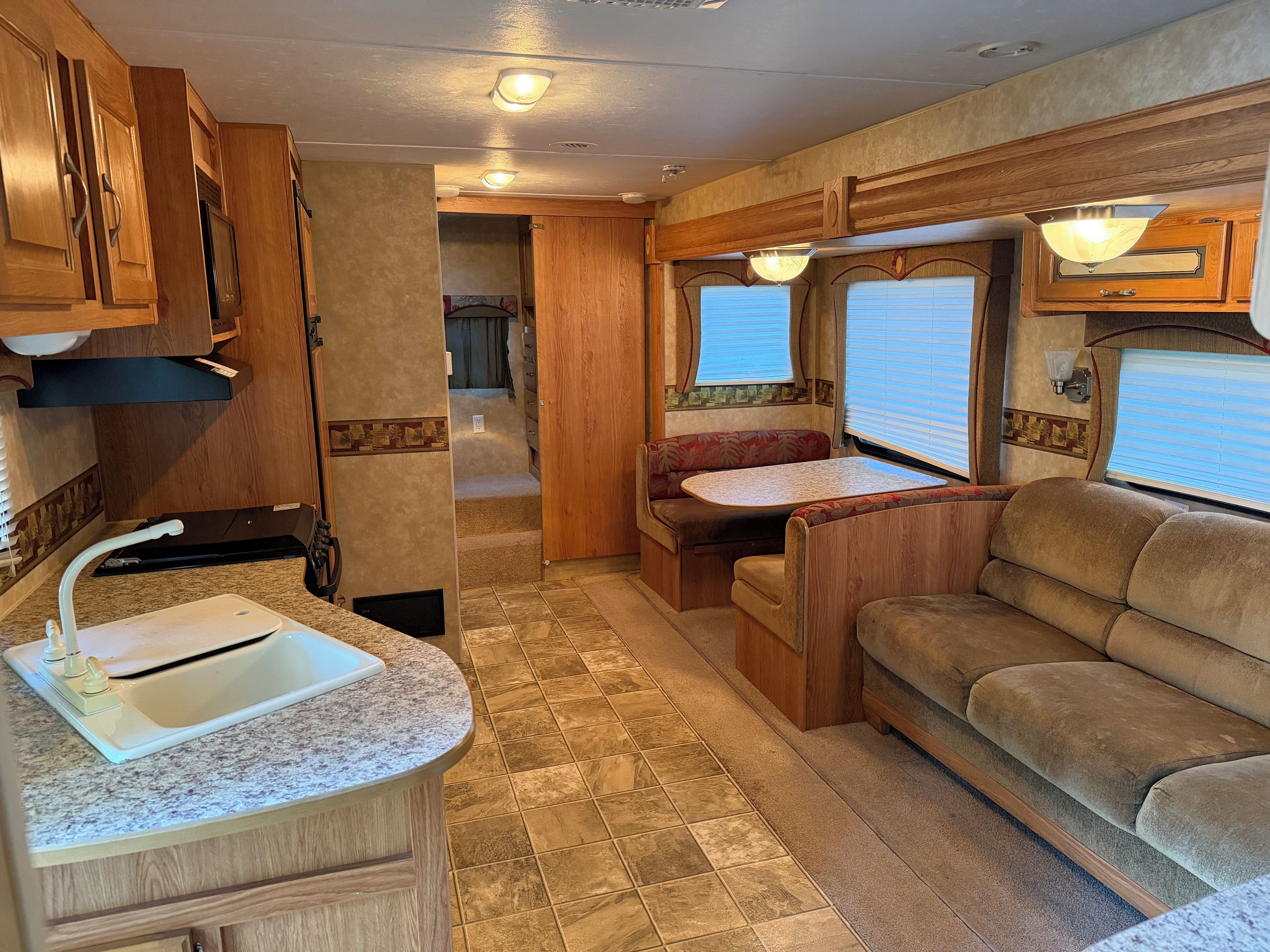 Un intérieur de camping-car compact comprenant un coin cuisine, un espace repas et un coin salon.