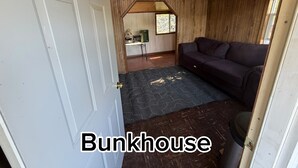 A bunkhouse interior with a wooden ceiling, a couch, a door, and a window.