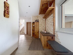 A hallway with a wooden bench, a stone wall, and a wooden cabinet with decorative items. - Alpenblick by Interhome (See)