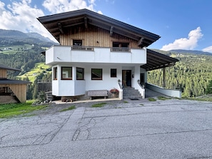 A two-story building with a balcony, a staircase leading to the entrance, and a view of a mountainous landscape. - Alpenblick by Interhome (See)