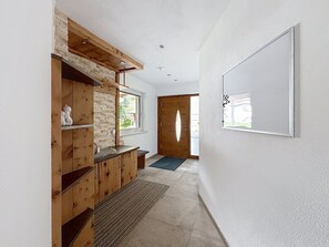 A hallway with a wooden cabinet, a rug, and a door leading to an outdoor area. - Alpenblick by Interhome (See)