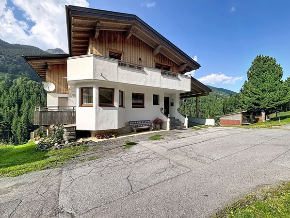 A two-story building with a balcony, a satellite dish, and a small garden area. - Alpenblick by Interhome (See)
