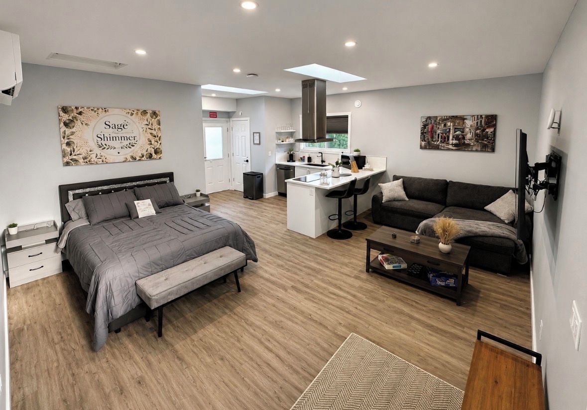 A modern living space with a bed, sofa, and a small kitchen area.