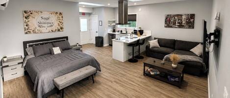 A modern living space with a bed, sofa, and a small kitchen area.