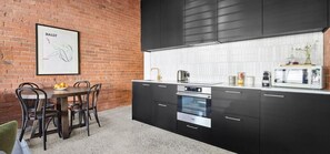 Una cucina moderna con mobili neri, un piano di lavoro bianco e una zona pranzo con tavolo e sedie.