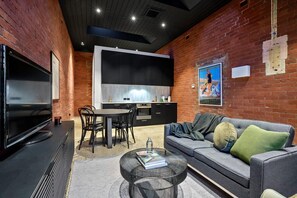 Un soggiorno moderno con una TV a schermo piatto, un divano, un tavolino da caffè e una zona pranzo con sedie e tavolo.