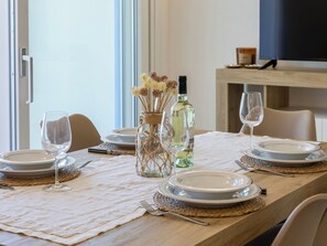 A dining table set with plates, glasses, and a bottle of wine, with a vase of dried flowers in the center. - La perla di mare 6 by Interhome (Valledoria)