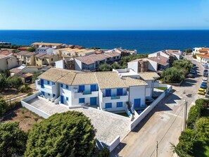 A coastal residential area with a prominent white building featuring blue accents, surrounded by other houses with similar architecture. - La perla di mare 6 by Interhome (Valledoria)