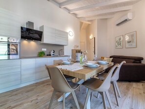 A modern kitchen with built-in appliances, a dining area with a wooden table and chairs, and a living area with a sofa. - La perla di mare 6 by Interhome (Valledoria)