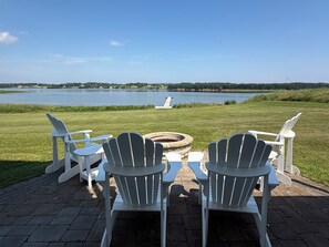 A lakeside seating area with Adirondack chairs and a fire pit.
