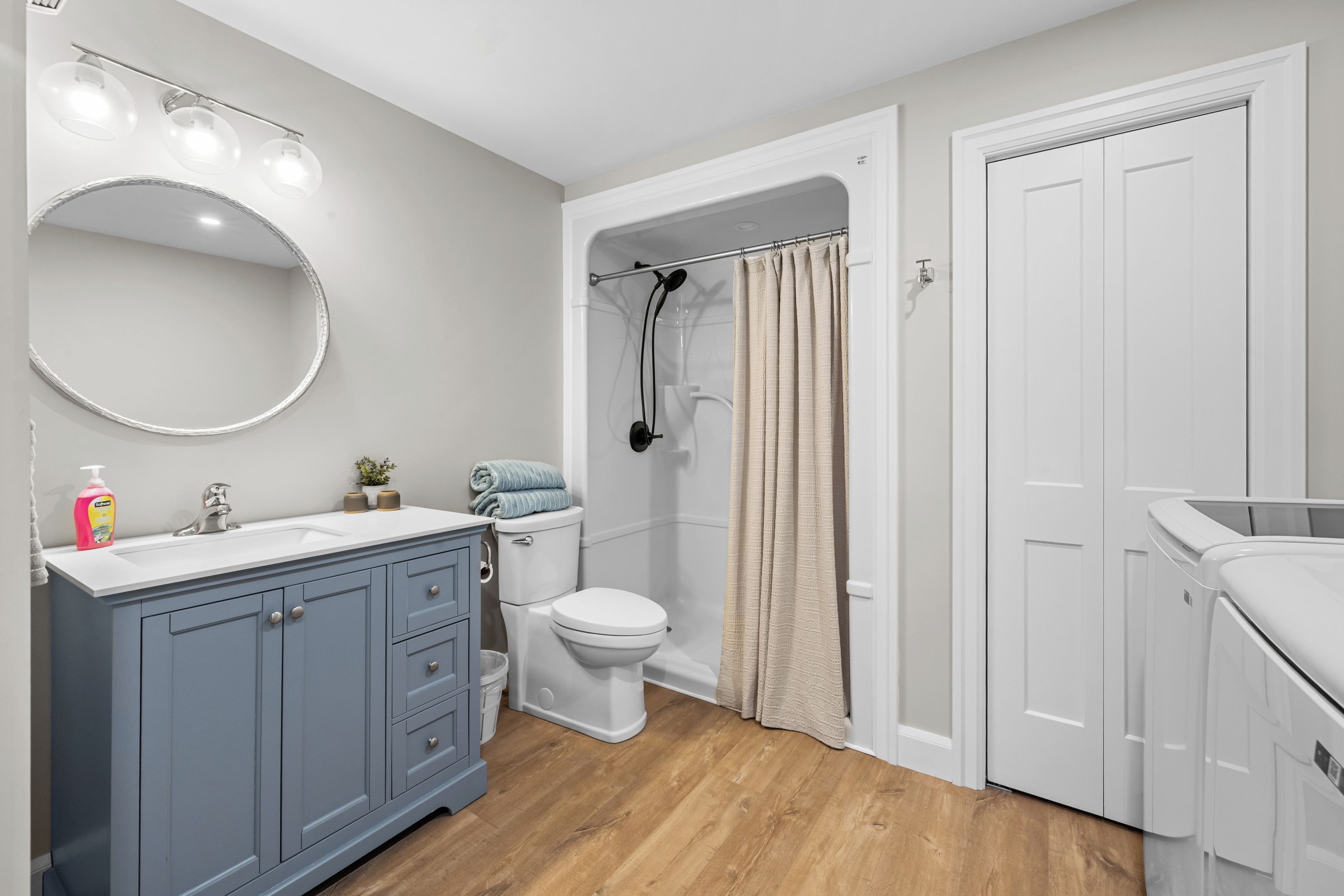A bathroom with a white sink, blue cabinets, a toilet, and a shower area.