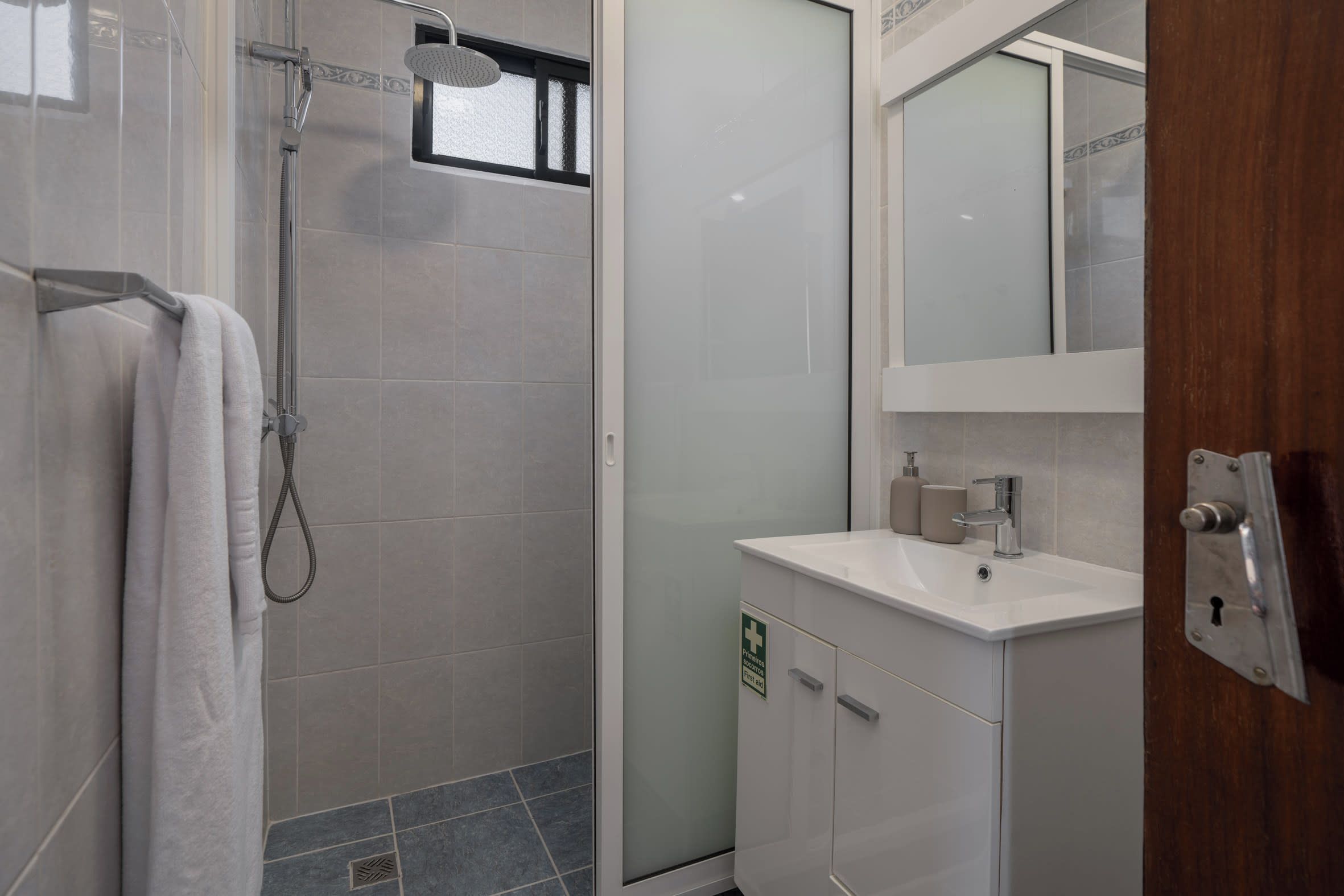 Un baño moderno con ducha, lavamanos y espejo.