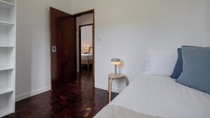 Une chambre à coucher avec un lit, une lampe de chevet et une porte en bois donnant sur une autre pièce.