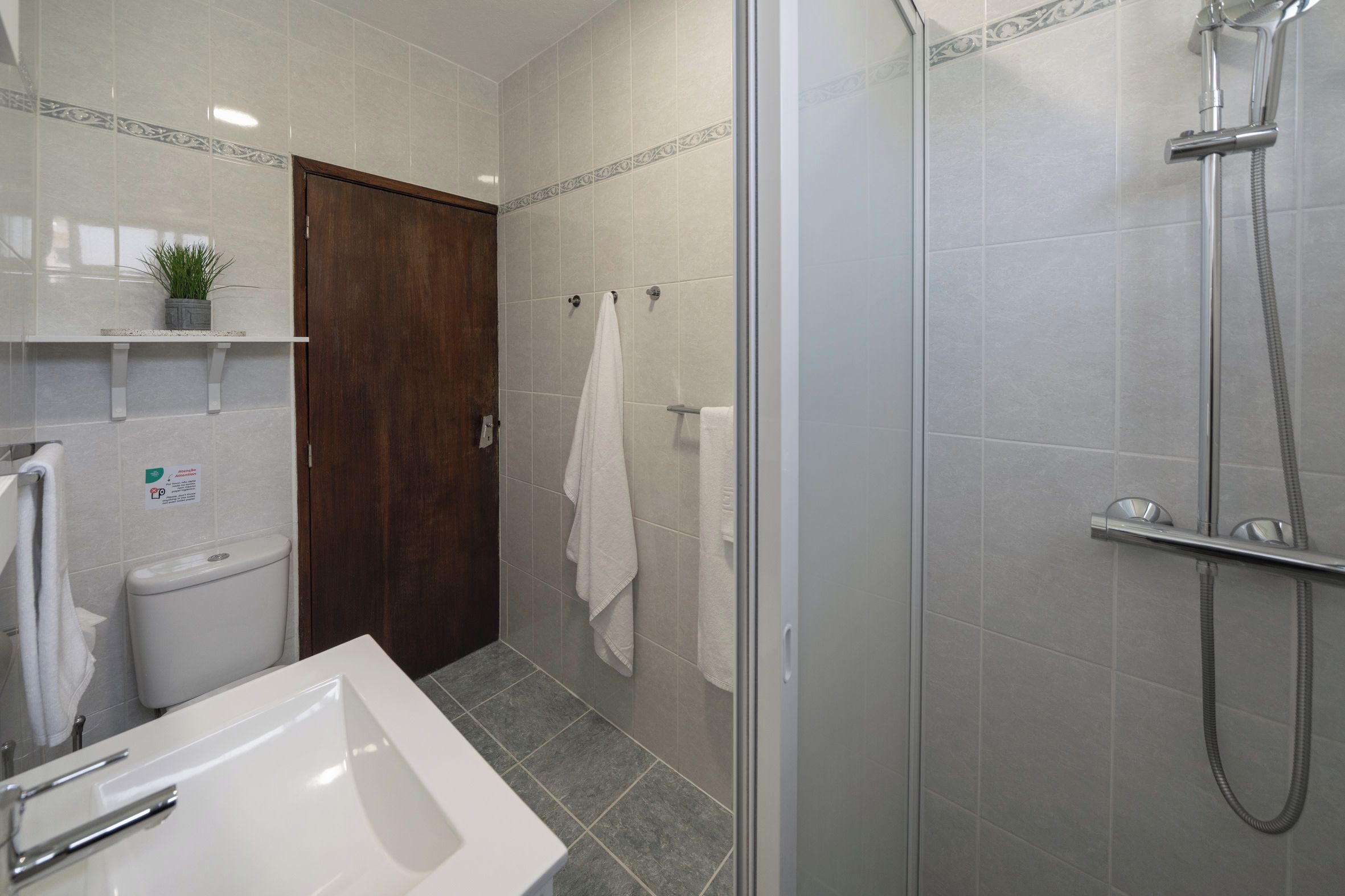 Une salle de bain avec douche, toilettes et lavabo.