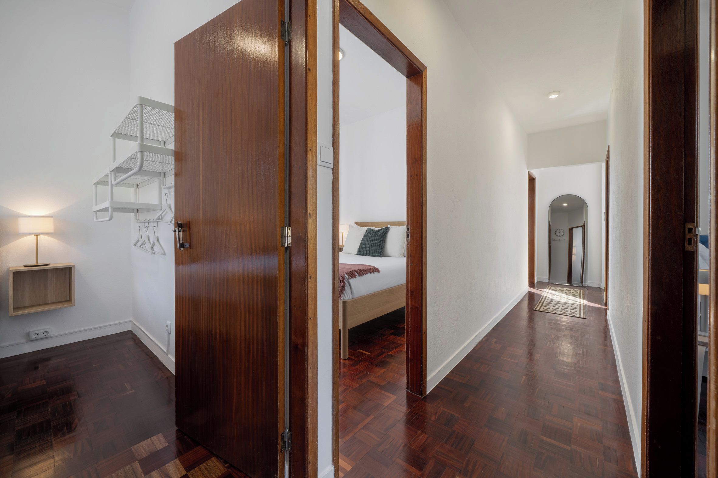 A modern interior with a wooden door, a staircase, a bed, and a hallway leading to another room.