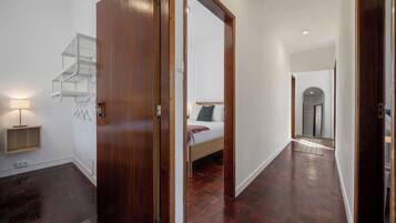A modern interior with a wooden door, a staircase, a bed, and a hallway leading to another room.