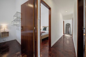 Interior moderno com porta de madeira, escada, cama e corredor que dá para outro quarto.