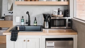 A kitchen with a stainless steel refrigerator, a coffee maker, and a microwave on the countertop. - The A-Frame · Hot Tub, Fire Pit, 30 min to Waco (Valley Mills)