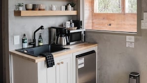 A kitchen with wooden shelves, a coffee maker, a microwave, and a window with blinds. - The A-Frame · Hot Tub, Fire Pit, 30 min to Waco (Valley Mills)
