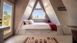 A bedroom with a sloped ceiling, a bed with pillows, a window, and a wooden floor. - The A-Frame · Hot Tub, Fire Pit, 30 min to Waco (Valley Mills)
