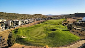 A golf course with a putting green, sand bunkers, and a clubhouse with modern architecture. - Luxury Golf Course-View - Heated Pool & Hot Tub (Hurricane)