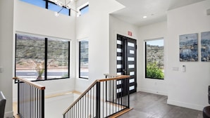 A modern interior with a staircase, large windows, and artwork on the walls. - Luxury Golf Course-View - Heated Pool & Hot Tub (Hurricane)