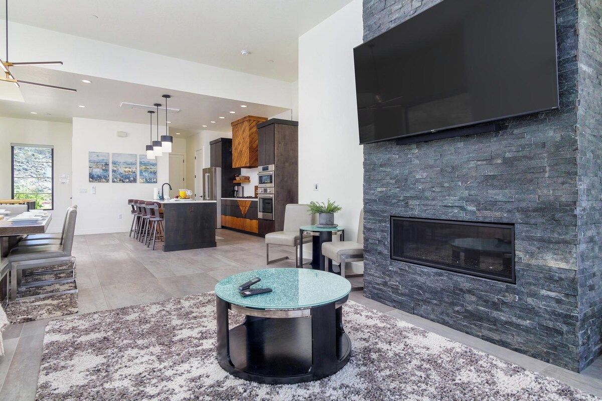 A modern living space with a fireplace, a dining area, and a kitchen.