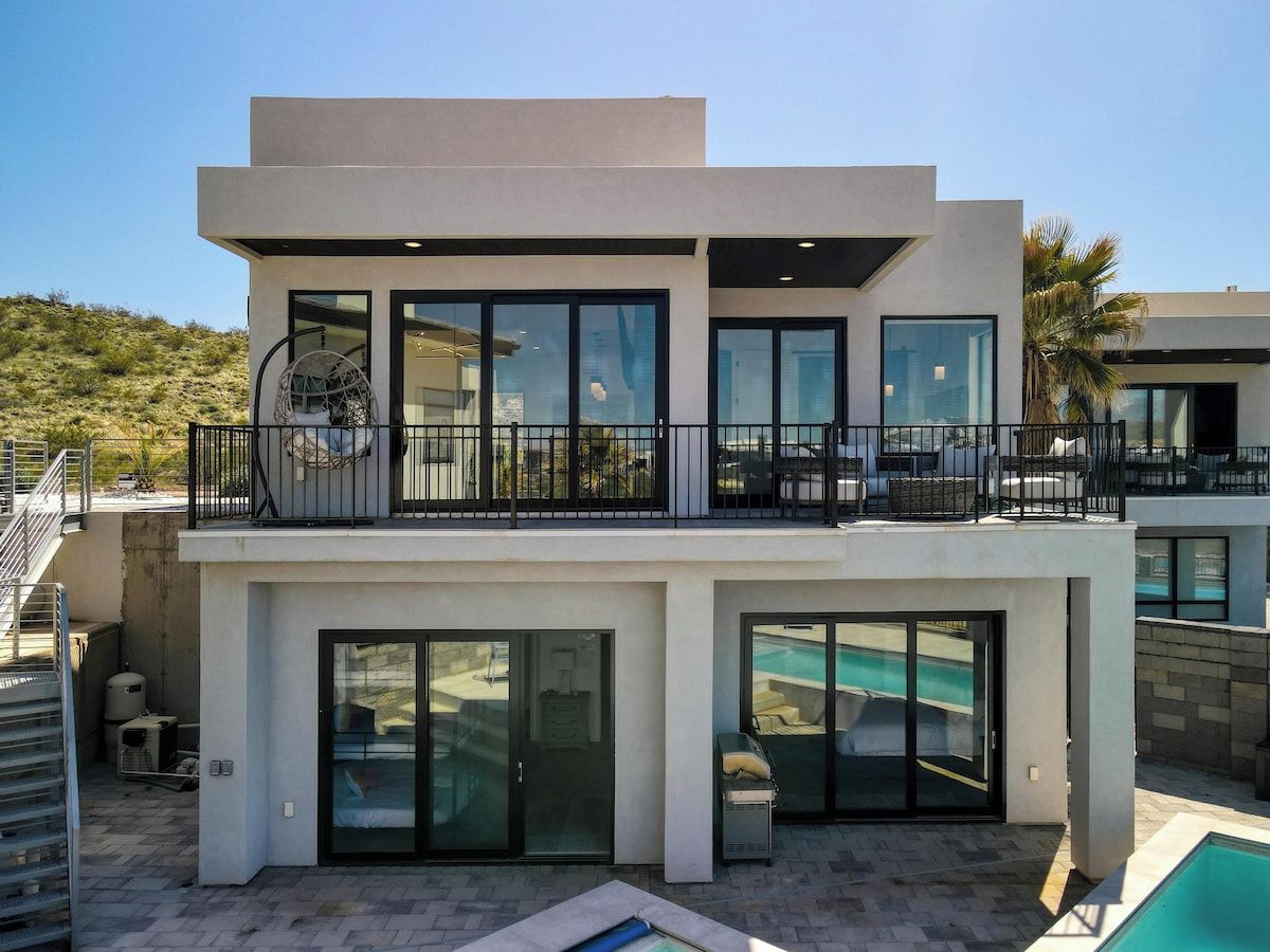 A modern two-story house with a balcony, a swimming pool, and a garage.