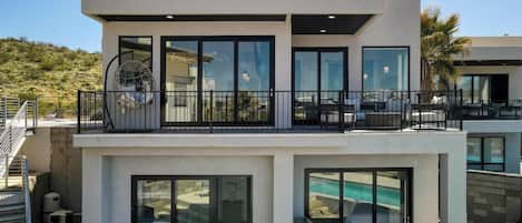Une maison moderne à deux étages, dotée d’un balcon, d’une piscine et d’un garage.