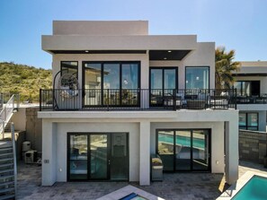 Ein modernes, zweistöckiges Haus mit Balkon, Swimmingpool und Garage.