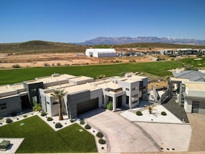 A modern building complex with multiple structures, a parking area, and a green lawn. - Luxury Golf Course-View - Heated Pool & Hot Tub (Hurricane)