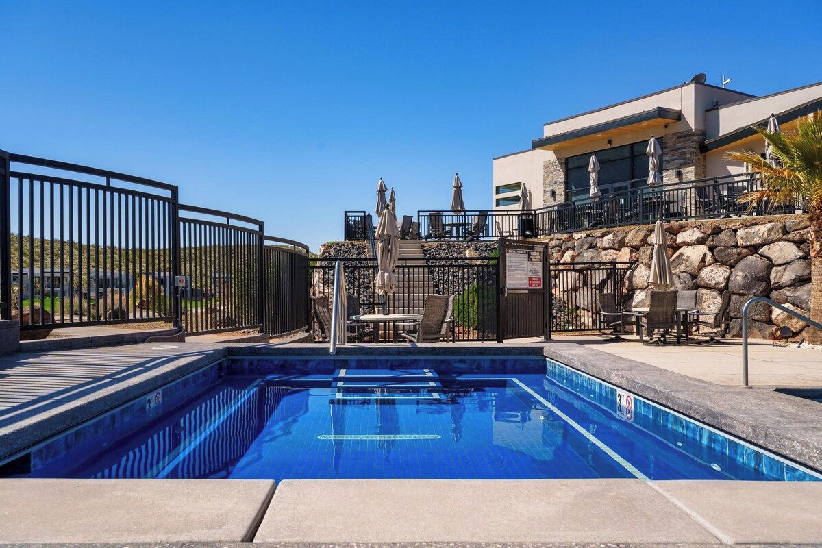 A swimming pool with a stone wall and outdoor seating area.