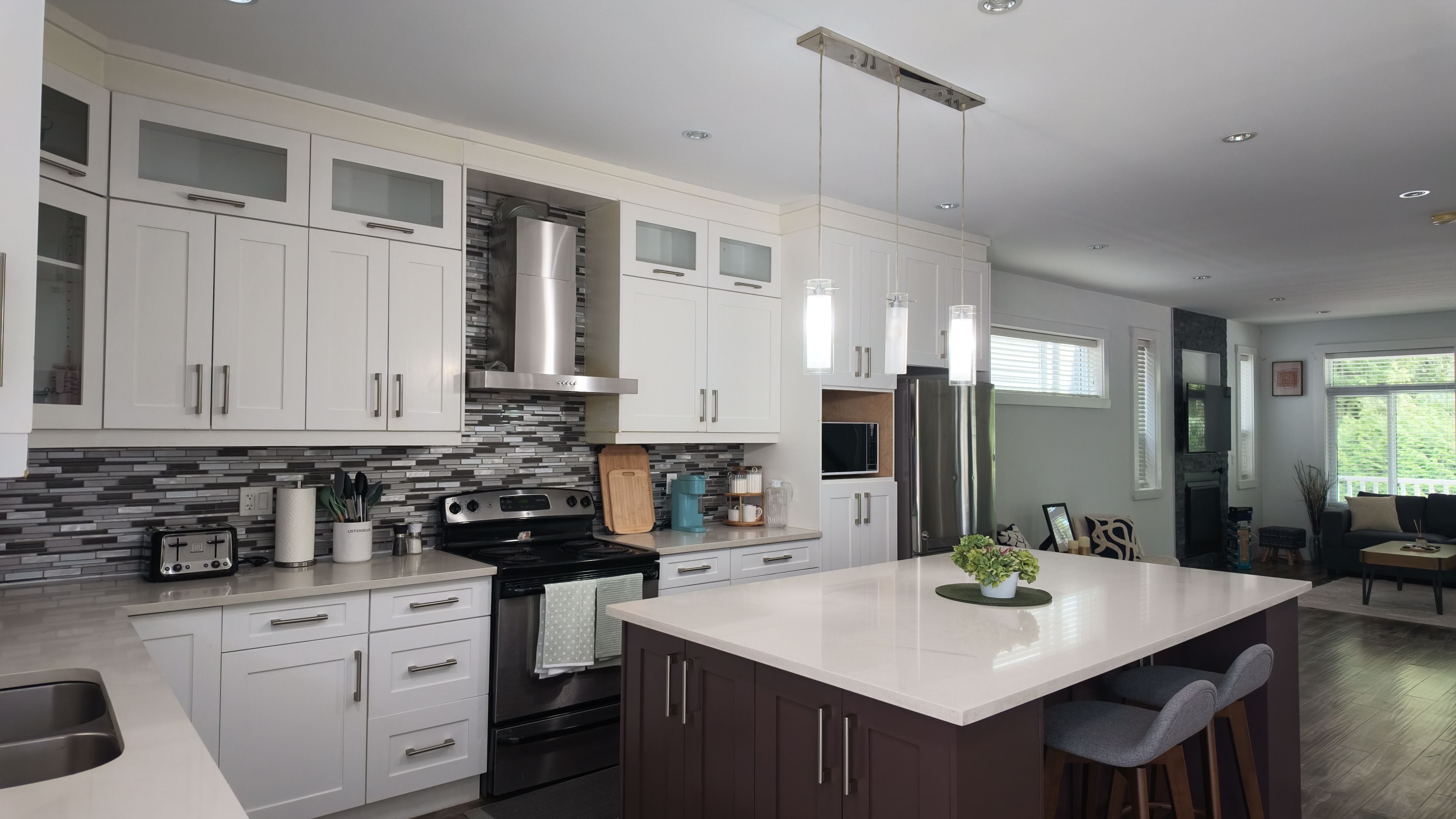 A modern kitchen with white cabinetry, a central island, stainless steel appliances, and a backsplash.