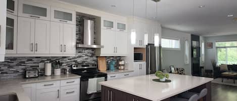 A modern kitchen with white cabinetry, a central island, stainless steel appliances, and a backsplash.