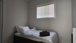 A single bed with white bedding and a window with blinds. - Home Away From Home - Surrey (Surrey)