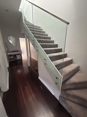 A staircase with glass railings and carpeted steps. - 4-bedroom house in amazing Dover Heights with cool AC (Dover Heights)