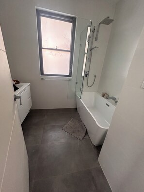 Un baño moderno con ducha, inodoro y ventana.