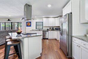 A modern kitchen with white cabinets, stainless steel appliances, and a central island. - Private Pool Retreat, Spacious 3BR + Large Yard (Brandon)