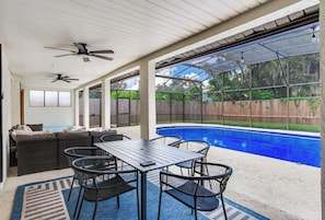 Área externa coberta com piscina, assentos e ventiladores de teto.