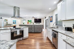 A modern kitchen with a built-in oven, a stovetop, and a granite countertop. - Private Pool Retreat, Spacious 3BR + Large Yard (Brandon)