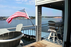 A deck with a view of a body of water, a flag, and outdoor furniture. - Bridgepointe Lake Escape (Osage Beach)