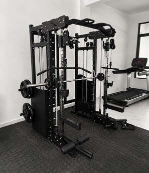 A gym with a multi-gym system, a treadmill, and a weight bench. - 2BR Near JKIA with Pool, Gym, Security, amenities & Free Parking (NAIROBI)