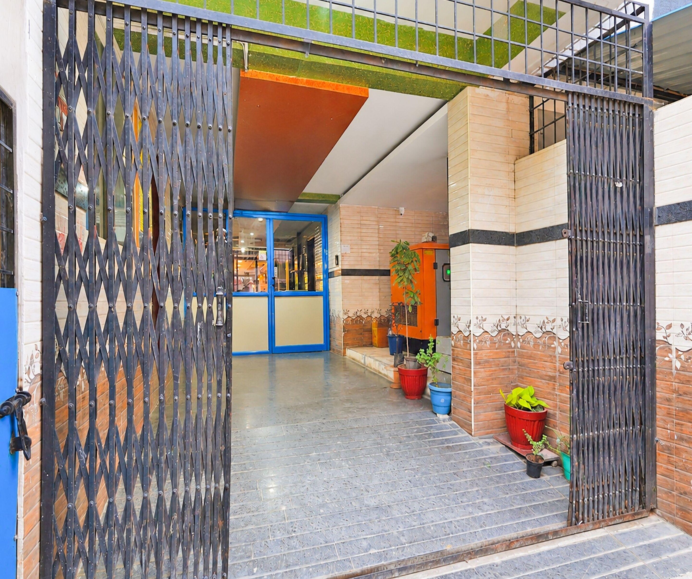 A gated entrance to a building with a blue door, potted plants, and a tiled floor.
