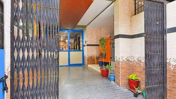 A gated entrance to a building with a blue door, potted plants, and a tiled floor.