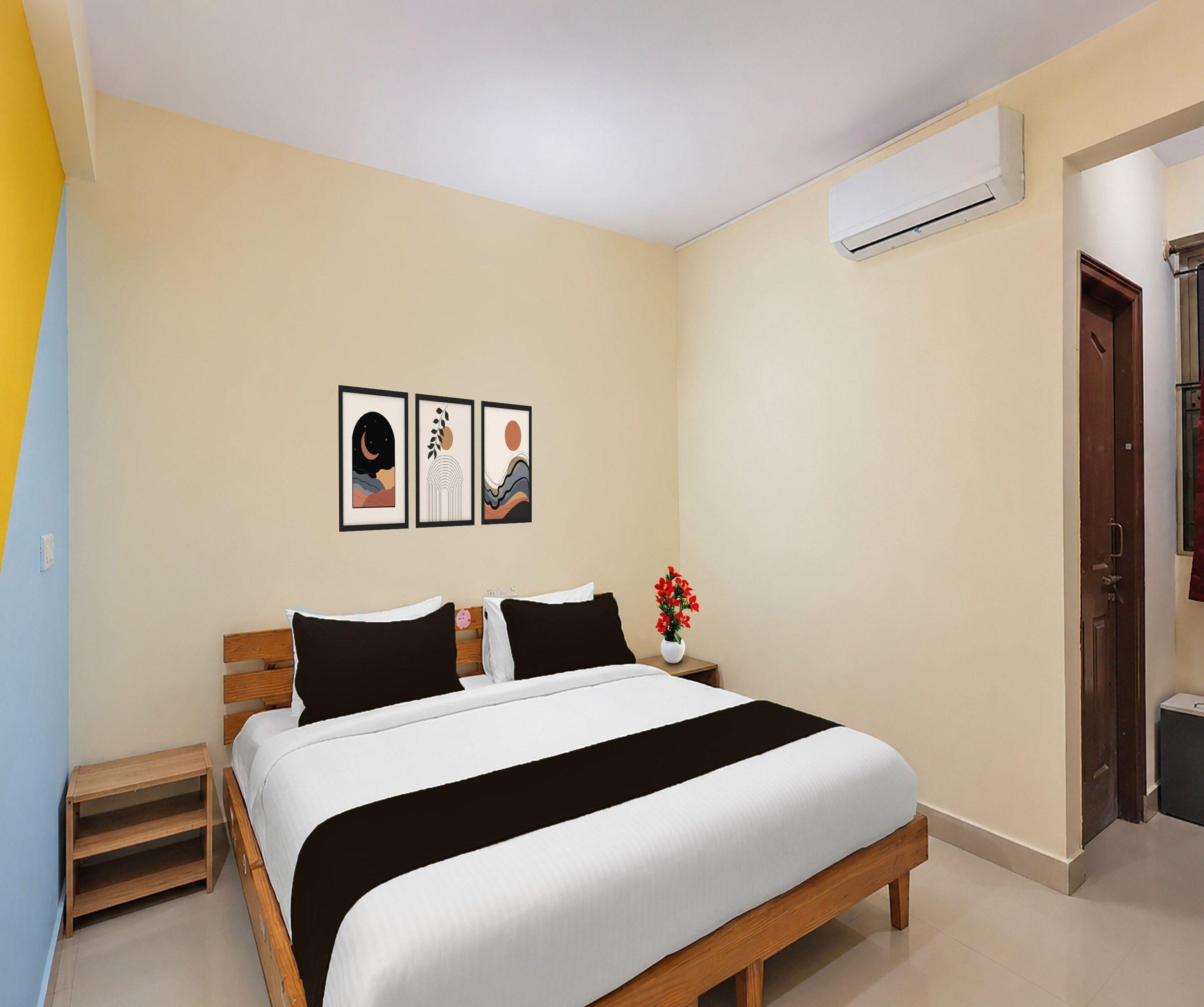 A bedroom with a bed, bedside tables, a wall-mounted air conditioner, and framed artwork.