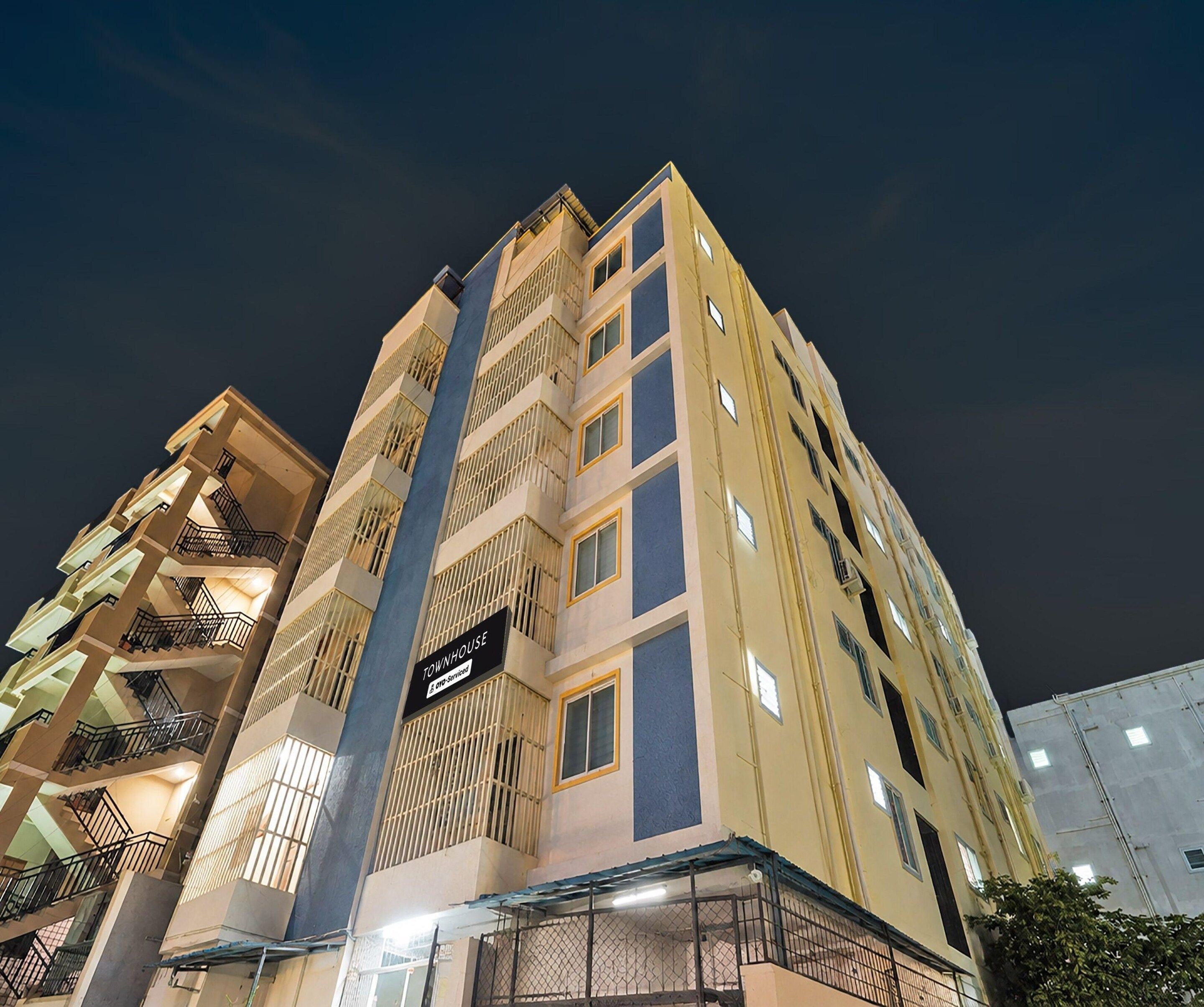 A multi-story hotel with a prominent vertical design, balconies, and a sign indicating it is a serviced property.