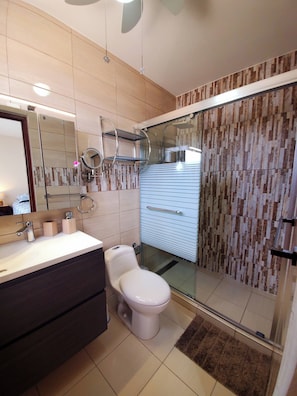 A modern bathroom with a toilet, vanity, and a glass shower enclosure. - Modern Relaxing Vacation Villa (Oranjestad)