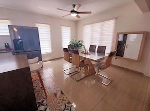 A modern dining area with a glass table, metal chairs, and a ceiling fan. - Modern Relaxing Vacation Villa (Oranjestad)