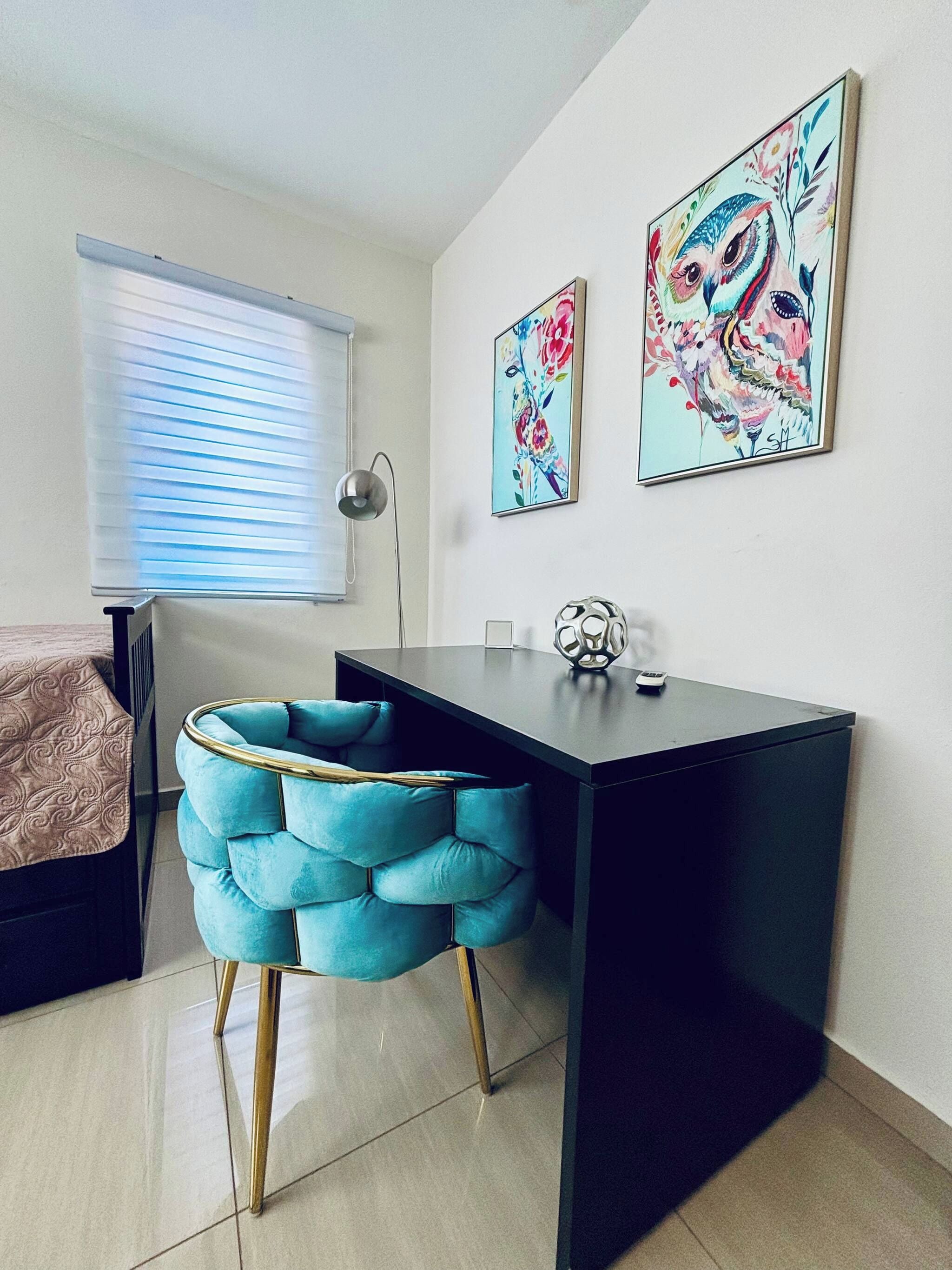 Ein modernes Schlafzimmer mit einem Bett, einem Schreibtisch und zwei an der Wand befestigten Kunstwerken.